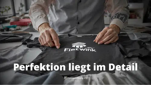 Nahaufnahme einer professionellen Qualitätskontrolle im Textildruck: Ein Experte inspiziert mit Präzisionswerkzeugen sorgfältig die Druckqualität auf einem Kleidungsstück. Im Hintergrund sind moderne Druckanlagen zu sehen.
