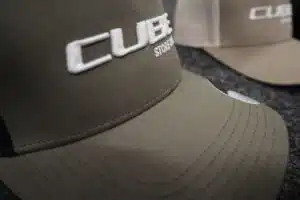 Khakifarbene Cap mit weißem, erhaben gesticktem CUBE-Logo – Beispiel für Logo-Stickerei auf Arbeitskleidung.